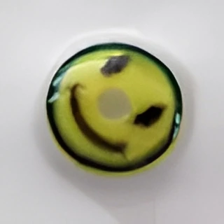 Round yellow object with a worn smiley face design, featuring black spots and a central hole, on a white background.