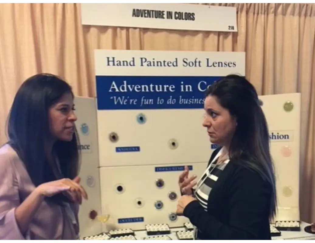 Two women are talking to each other at a trade show.