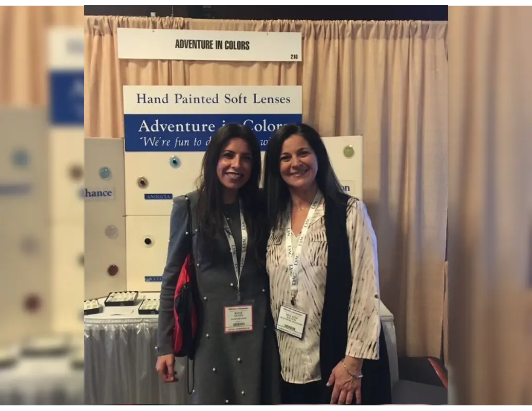 Two women standing next to each other in front of a sign.
