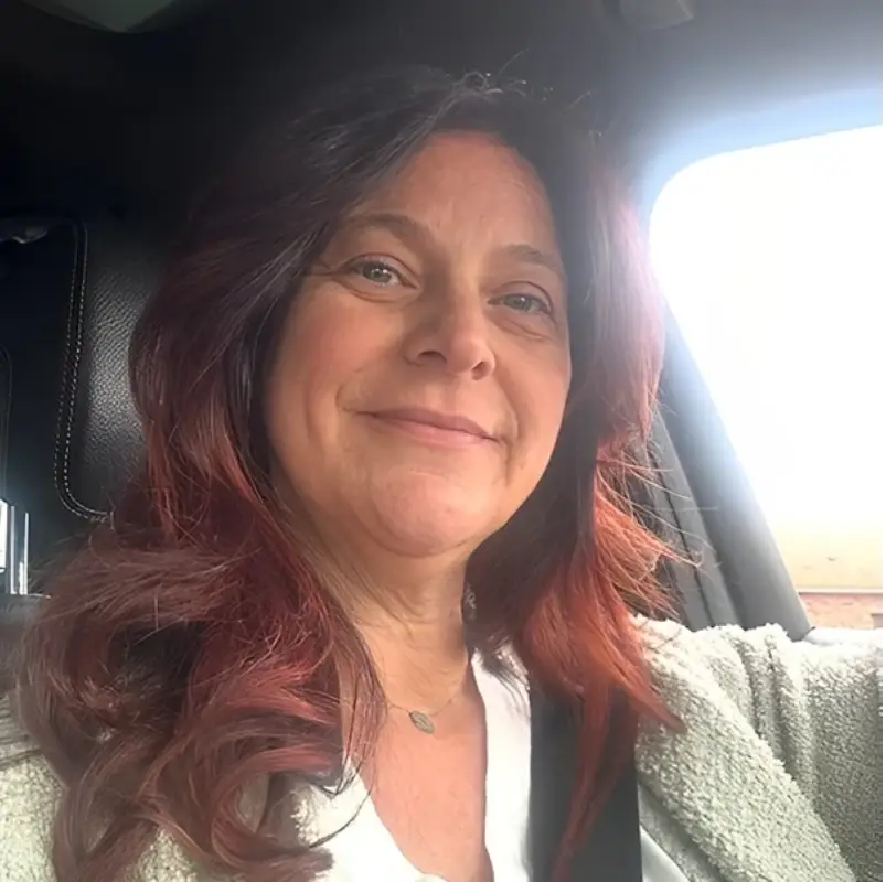 A woman with red hair sitting in the back of a car.