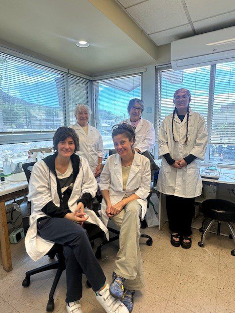 Five people in lab coats, smiling together.